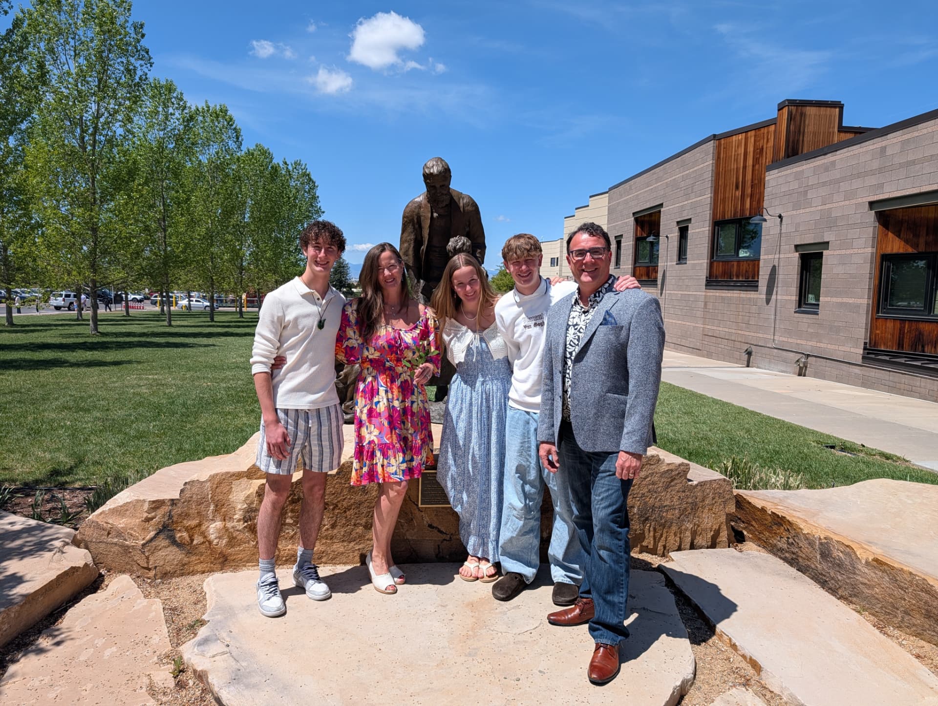 Family photo outdoors in front of a bronze statue on a bright sunny day